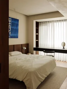 Modern minimalist bedroom featuring a bed with white bedding, curtains, and a glass window.