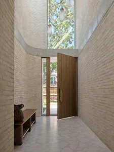 Modern entrance with a curved brick ceiling and a wooden door.
