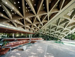 Modern interior space with concrete ceiling and glass walls featuring geometric patterns and a contemporary design.