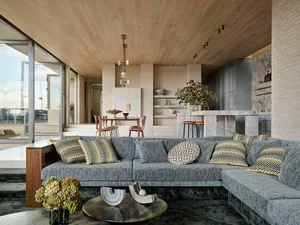 A modern living room with a large sectional sofa, patterned cushions, and a round coffee table.