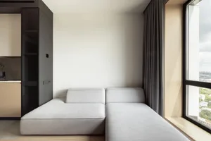 Modern living room featuring a fabric sofa and large windows with a view of the outdoors.