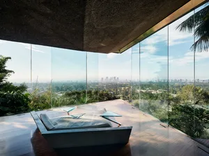 A modern living room featuring glass walls overlooking a lush garden.