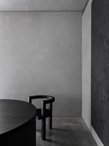 Minimalist interior with concrete table, wooden chair, and smooth concrete walls and floor.