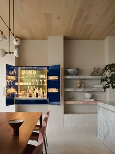 A modern interior design featuring a living room with a bar area equipped with marble, concrete, and wooden elements.