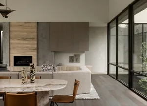 Modern living room with a combination of wooden and marble materials, featuring a cozy sofa and a sleek dining table.