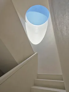 A minimalist staircase made of concrete, featuring a circular window at the top.