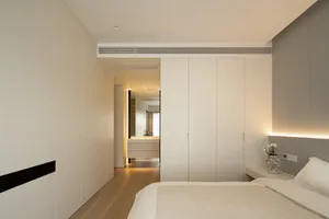 Modern minimalist bedroom with white furniture and wooden floor.