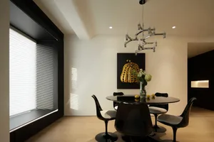 Modern minimalist dining room featuring a glass table with black and white chairs, a chandelier, and a black and yellow abstr