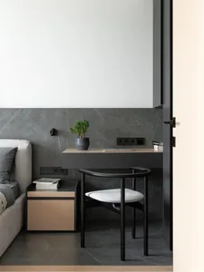 A minimalist workspace with a marble desk, wooden chair, and metal accents