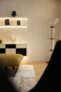 A modern living room featuring wooden flooring, glass walls, and leather seating with metal accents.