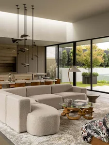 A modern living room featuring a large, textured fabric sofa and a round, wooden coffee table.