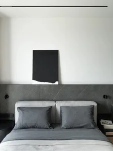 Minimalist bedroom with concrete headboard, metal accents, and gray fabric bedding.