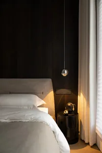 Minimalist bedroom featuring upholstered furniture and glass elements.