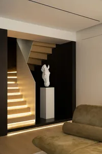 A modern staircase with illuminated steps and a sculpture of a horse's head on a pedestal.