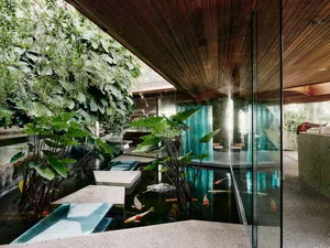 A modern interior design featuring a water pond with wood, concrete, and glass materials.
