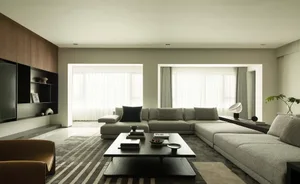 Modern living room featuring a concrete flooring, large windows, and a gray sectional sofa.