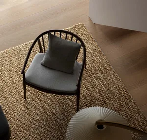 A gray cushion on a wooden chair in a minimalist living room setting.