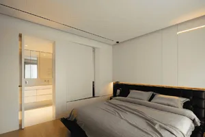 Modern bedroom with white walls and neutral bedding.
