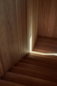 A wooden staircase with sunlight filtering through, creating a warm and inviting atmosphere.