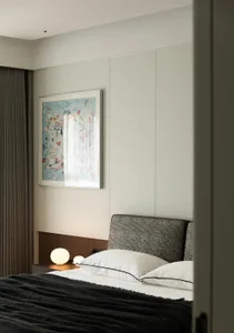 Minimalist bedroom with a textured grey bedspread, white pillows, and a contemporary artwork.