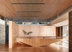 Modern white marble kitchen with wooden cabinets and ceiling.