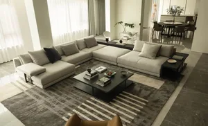 A modern living room featuring a grey fabric sofa, black coffee table, and a striped rug.