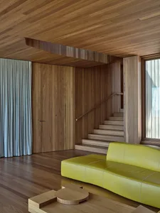 A modern living room featuring a yellow sofa and wooden paneling