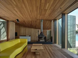 A modern minimalist living room featuring a wooden floor, yellow sofa, and a fireplace.
