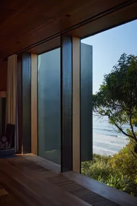 A modern window design with a glass view of the ocean and lush greenery.