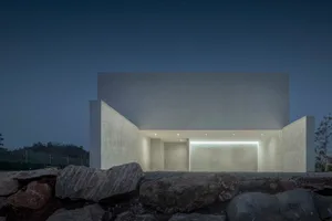 A modern building constructed with concrete materials, featuring a minimalist design with clear lines and geometric shapes.