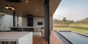 A modern industrial living space with concrete countertops and wooden flooring, featuring a poolside area with a fire pit and