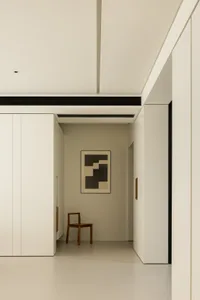 A minimalist white interior space with a chair and abstract wall art