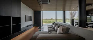 A modern living room featuring a concrete and glass sofa with a large floor-to-ceiling window.