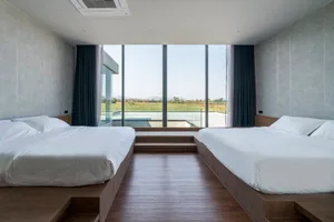 Modern, minimalist bedroom with concrete walls and polished wooden floor, featuring twin beds with wool bedding and views of