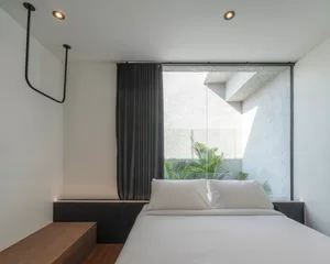 Minimalist bedroom with large glass window and concrete furniture.