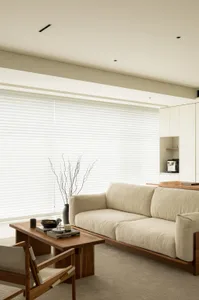 A modern minimalist living room with neutral tones, featuring a sleek sofa, wooden coffee table, and decorative vase.