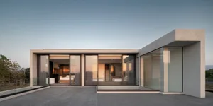 Modern minimalist residential interior with glass walls and concrete finishes.