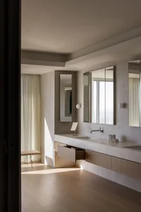 Modern minimalist bathroom featuring concrete walls, a floating wooden vanity, and large mirrors.
