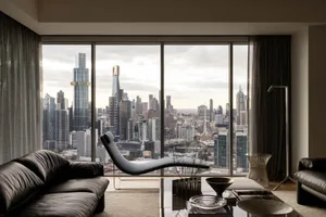 Modern living room with concrete, glazed, and metal furniture overlooking a cityscape.