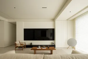 A modern living room with a neutral color scheme, featuring a minimalist design with a large screen television, a wooden coff