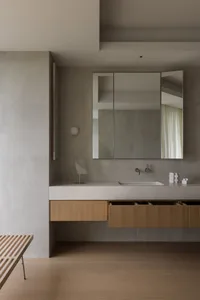 Modern minimalist bathroom featuring a floating wooden vanity with a white countertop, a large mirror, and a floating bench.