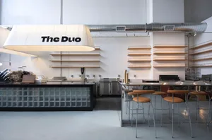An interior of a modern coffee shop with a glass counter and wooden shelves.