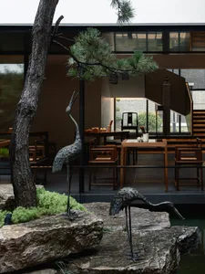 Modern restaurant interior with wooden tables, stone accents, metal sculptures, and glass features