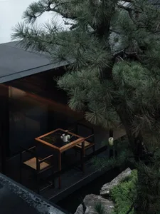 A modern coffee shop interior with a wooden table and chairs, black marble table top, and greenery.