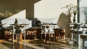 A modern cafe interior with wooden seating and marble tables and countertops.