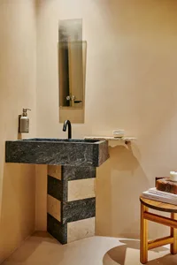 Modern indoor bathroom featuring a stone sink with a sleek black faucet and a rectangular mirror above it, set against a text