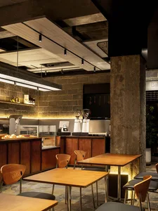 Industrial-style coffee shop with concrete walls, wooden tables, and metal stools.
