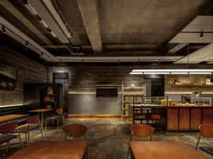 工業風餐廳室內，混凝土牆面、木質餐桌與金屬元素。