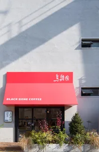 Modern coffee shop storefront with red awning and glass front door.