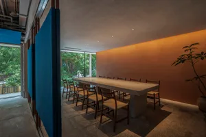Modern conference room featuring a long, white terrazzo table surrounded by wooden chairs and positioned against a textured, 